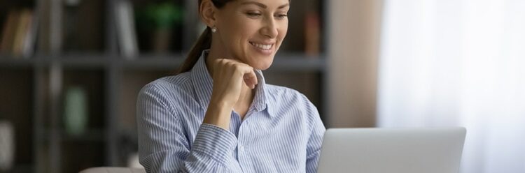 Attractive smiling business lady sit at workplace desk working on laptop. Concept of successful entrepreneur female, routine using computer, websurfing, modern tech usage and wi-fi connection concept